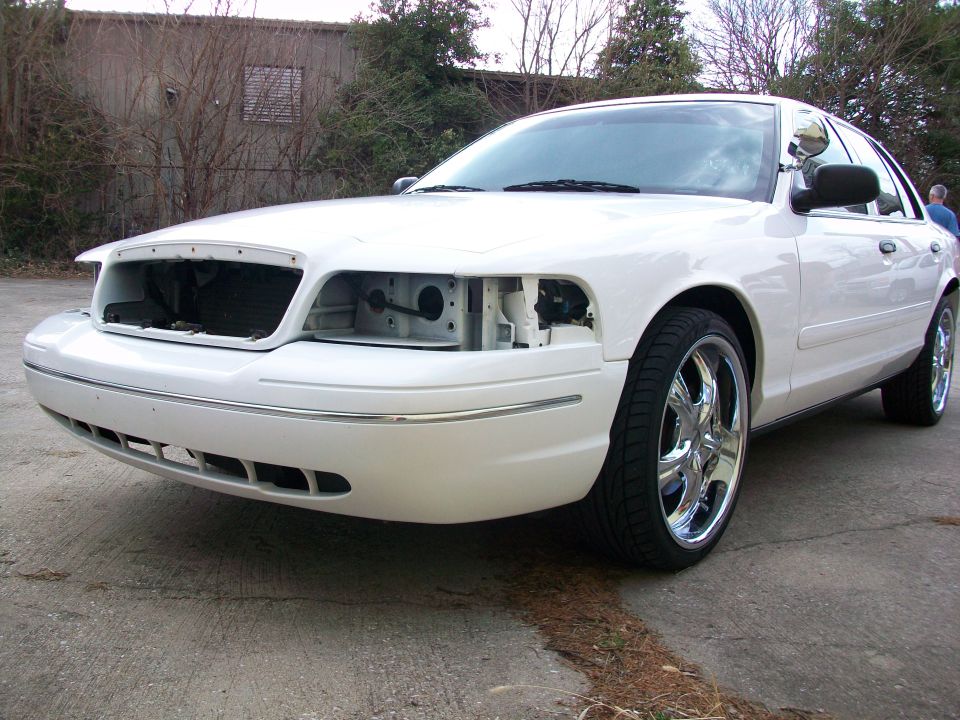 White 2003 Ford Crown Victoria, front view, missing headlights and grille, chrome wheels