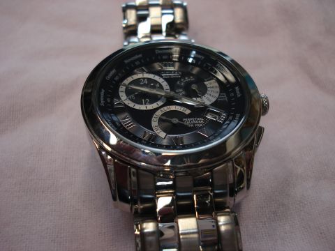 2000 Ford Crown Victoria - A close-up of a silver watch with a black dial, displaying time and calendar functions.