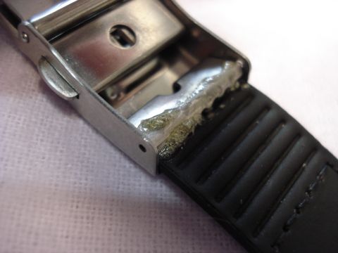 2000 Ford Crown Victoria - The metal clasp of a watch shows dried adhesive residue where it connects to the ribbed black strap.