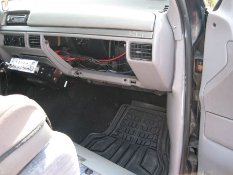 1994 Ford Bronco - The open glove box reveals wiring and a radio unit installed beneath the dashboard.