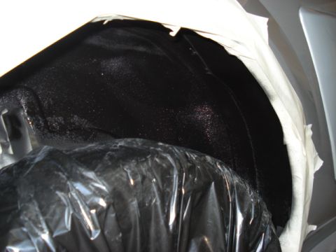 1998 Ford Taurus - Close-up view of a vehicle's wheel well interior, showing black undercoating and masking tape.