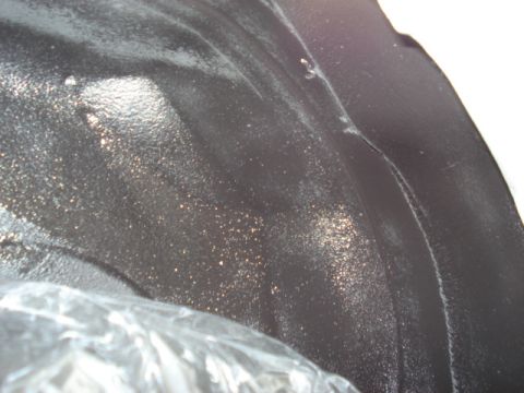 1998 Ford Taurus - Detail of a vehicle's wheel well, showing the textured undercoating and some reflective particles.