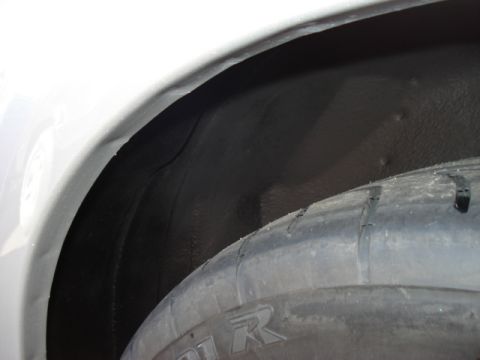 1998 Ford Taurus - Interior view of a vehicle's wheel well, showing the tire and black undercoating.