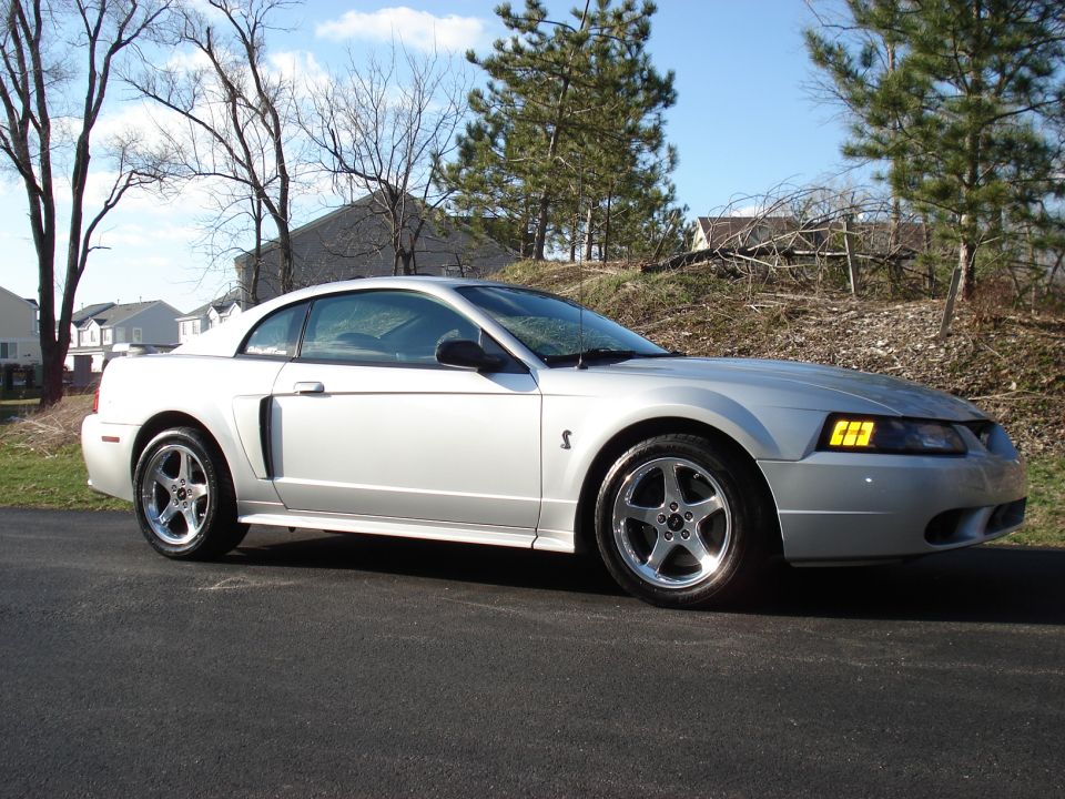 Silver coupe with side scoop and five-spoke wheels. Appears to be a 1999 Ford Mustang