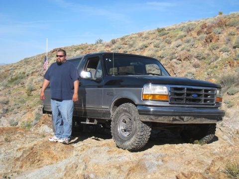 1994 Ford Bronco - A man stands next to a two-tone Ford Bronco in a desert landscape.