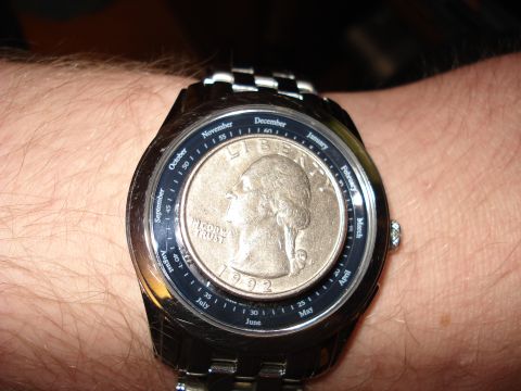 2000 Ford Crown Victoria - A watch is worn on a wrist, a quarter as its face and a monthly calendar dial.