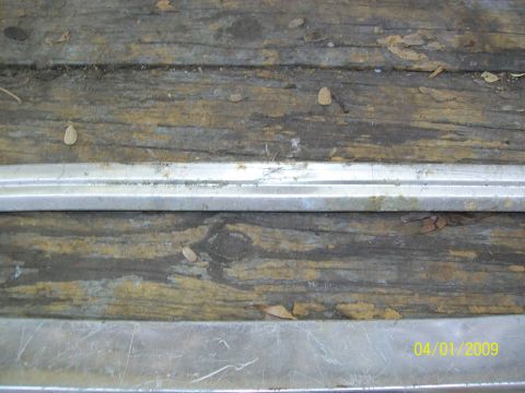 1972 Ford Ranchero - Close-up of a weathered wooden surface with metal trim, showing debris and a date stamp.