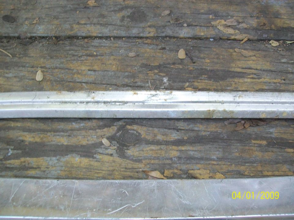 Wooden surface with two horizontal metal trim pieces and debris. Date stamp 04/01/2009 and SuperMotors.net logo visible