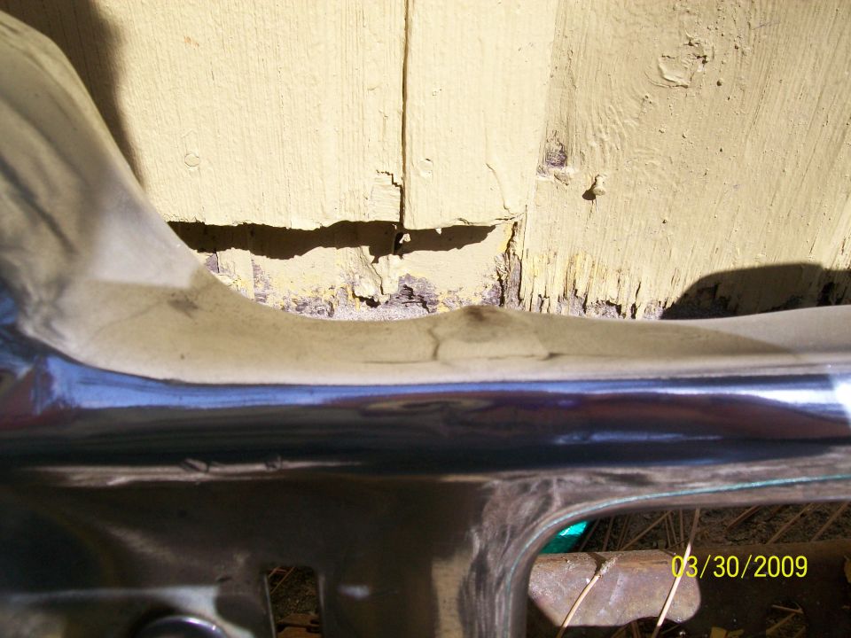 Chrome bumper below cracked and peeling painted wood paneling