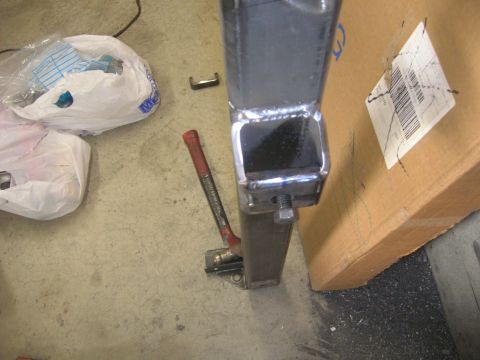 1996 Ford Bronco - Metal bracket assembly with jack attached to a square metal post, with bags and box in background.
