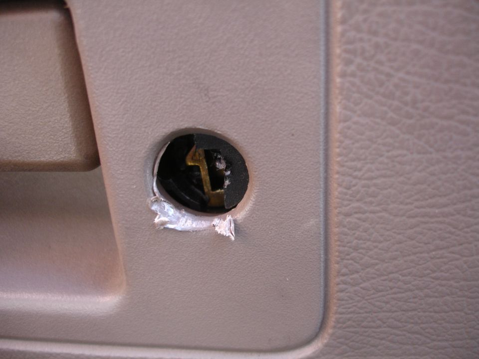 Close-up of a car's interior door panel showing a damaged lock cylinder