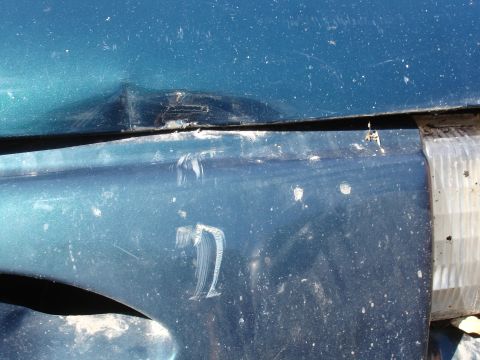 1995 Ford Taurus - The vehicle shows damage to the fender and headlight area, with visible scuff marks and dents.