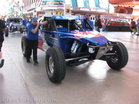 1990 Ford Bronco - man pushes a blue open desert race buggy with roof lights along the covered Fremont Street Experience in Las Vegas.