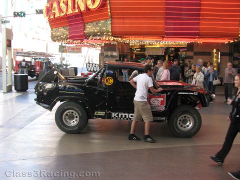 1990 Ford Bronco - man pushes a black off-road race truck numbered 6060 with KMC wheels past a casino on the Fremont Street Experience.