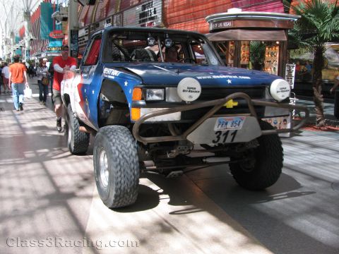 1990 Ford Bronco - Front view of a lifted patriotic off-road race truck numbered 311 with round lights and a Nevada plate on Fremont Street.