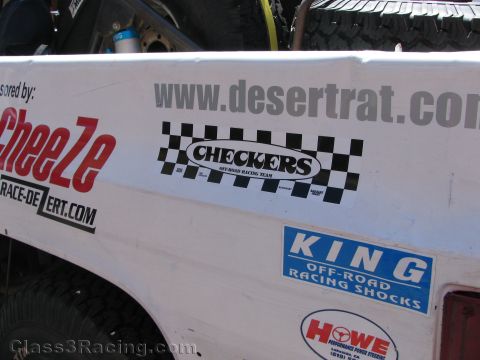 1990 Ford Bronco - Close-up of a white race truck side panel covered in sponsor decals including www.desertrat.com, Checkers and King shocks.