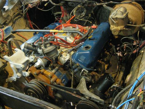 1979 Ford Bronco - The engine bay of a vehicle, showing the V8 engine with blue valve covers and various hoses and wires.