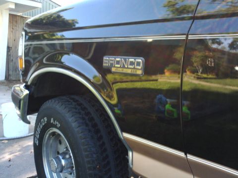 1994 Ford Bronco - A black 1994 Ford Bronco is shown from the front quarter, highlighting its side panel and wheel.
