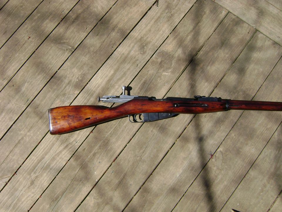 Wooden stock and metal receiver of a Mosin-Nagant rifle on a wooden deck