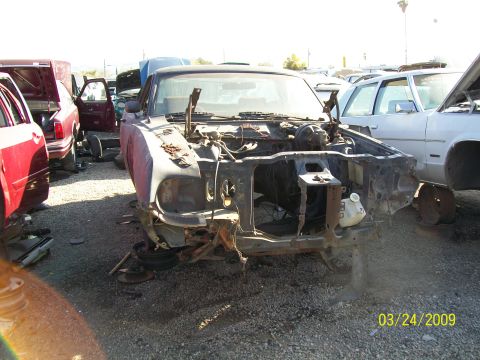 1972 Ford Ranchero - Car parts yard with a heavily damaged vehicle front end and other cars in the background.