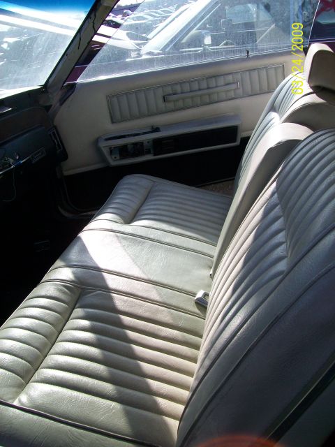 1972 Ford Ranchero - The interior of a vehicle features white vinyl seats and a matching door panel, with a date stamp visible on the window.