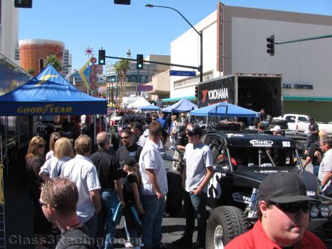 1990 Ford Bronco - busy outdoor automotive street fair crowd gathers near Goodyear and Yokohama tents with a black race truck no. 183.