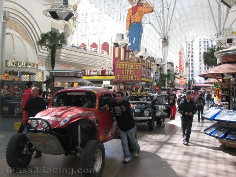 1990 Ford Bronco - red off-road race truck is pushed by a man down the covered Fremont Street Experience past souvenir shops and casinos.