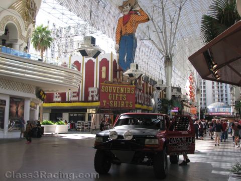 1990 Ford Bronco - red lifted off-road truck with roof light bar sits on the covered Fremont Street pedestrian mall beneath neon casino signage.