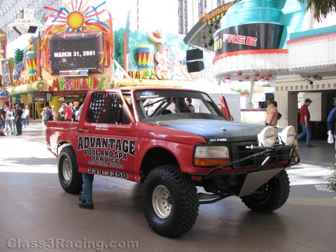 1990 Ford Bronco - red lifted off-road Ford truck lettered Advantage Pool and Spa Service sits under the Fremont Street canopy, a sign reading March 31, 2001.