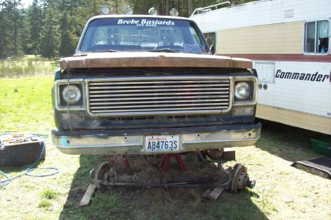 1976 Chevrolet C/K Pickup - This pickup truck is elevated on jack stands with its front axle detached, suggesting it is undergoing repairs or awaiting repairs.