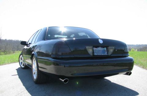 2003 Mercury Marauder - Rear view of a black 2003 Mercury Marauder parked on a paved surface with grass and trees in the background.