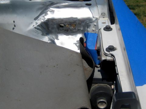1996 Ford Bronco - Close-up view of a vehicle's engine bay, showing damaged metal and a blue plastic component.