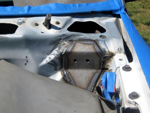 1996 Ford Bronco - A steel gusset plate with two drilled holes freshly MIG-welded onto the inner fender apron of a vehicle, the stitched weld bead running all…