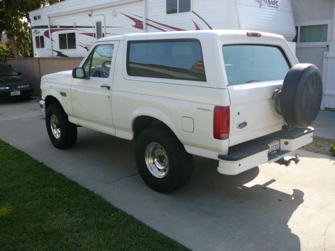 1988 Ford Bronco - This white Ford Bronco, likely from the early to mid-1990s, is parked in a driveway with a trailer behind it.