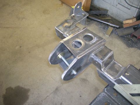 1996 Ford Bronco - A close-up view of a fabricated metal suspension component, likely for a vehicle, resting on a concrete floor.