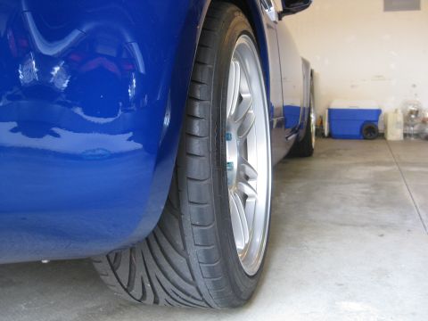 1990 Ford Probe - Close-up view of a blue car's rear wheel, aftermarket silver rims and performance tires.