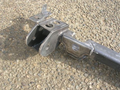 1996 Ford Bronco - A close-up view of a fabricated metal suspension component resting on a gravelly ground.