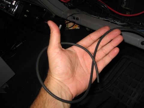 1994 Ford Bronco - A hand holds a black vacuum hose, with wiring and interior components visible in the background.