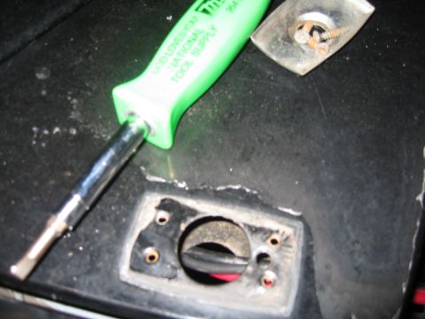 1994 Ford Bronco - Screwdriver and screw on a vehicle interior panel.