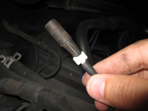 1994 Ford Bronco - A hand holds a vacuum hose, part of a vehicle's A/C system, against a dark, engine-like background.