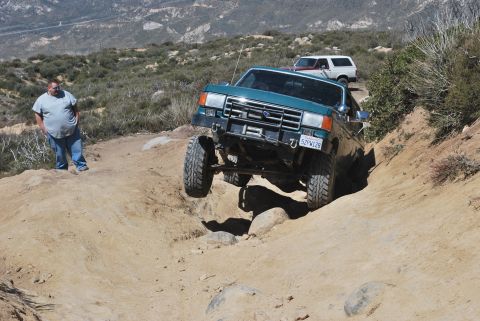 1996 Ford Bronco - Two Ford Broncos tackle a challenging off-road course on a sunny day.
