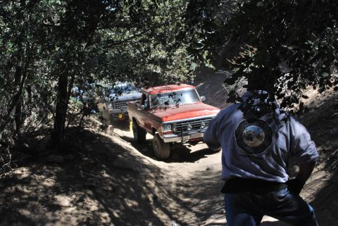 1996 Ford Bronco - Two trucks navigate a dusty trail through trees. The lead truck appears to be a 1978 Ford F-150.
