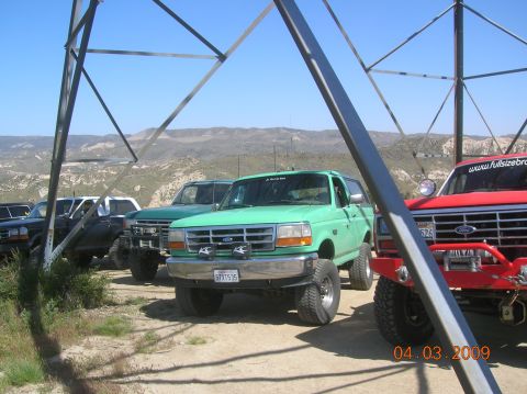 1985 Ford Bronco - Several off-road vehicles are parked together in a dusty, outdoor area with hills in the background.