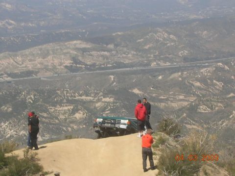 1985 Ford Bronco - Off-road vehicle precariously positioned on a cliff edge with onlookers.