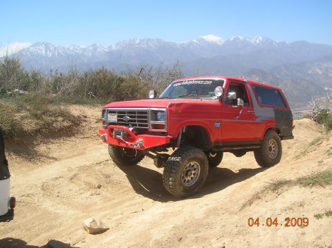 1985 Ford Bronco - This modified 1985 Ford Bronco navigates a dusty trail with mountains in the background.