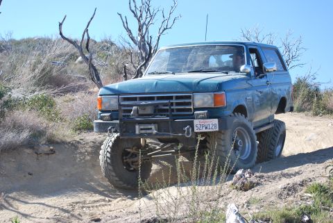 1996 Ford Bronco - A modified Ford Bronco navigates a off-road trail under a clear blue sky.