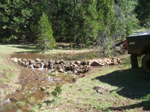 1994 Ford F-150 - The rear of a 1994 Ford F-150 is visible next to a small stream with a rock dam.