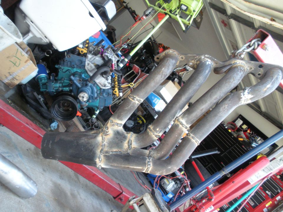 Custom exhaust manifold and engine components in a garage setting
