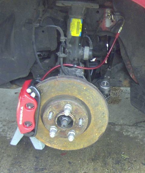 1997 Ford Taurus - Close-up of a red COBRA brake caliper and rotor assembly, part of a vehicle's suspension system.