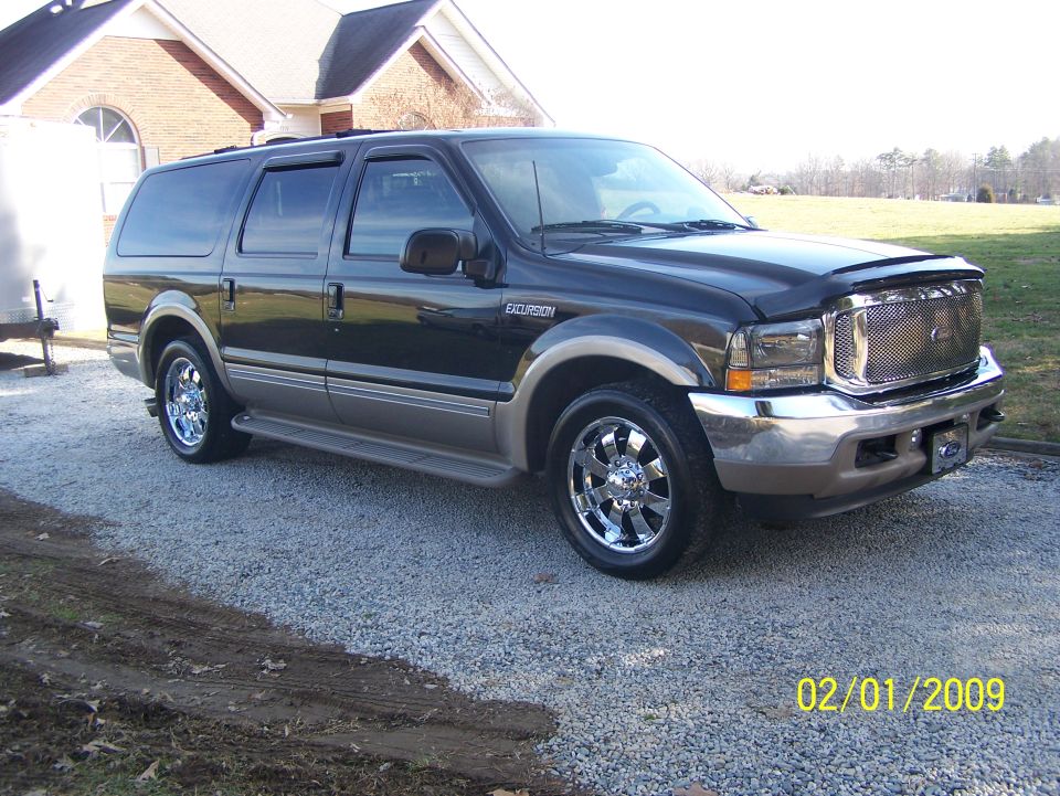Black Ford Excursion SUV with chrome wheels on gravel driveway, 3/4 front view